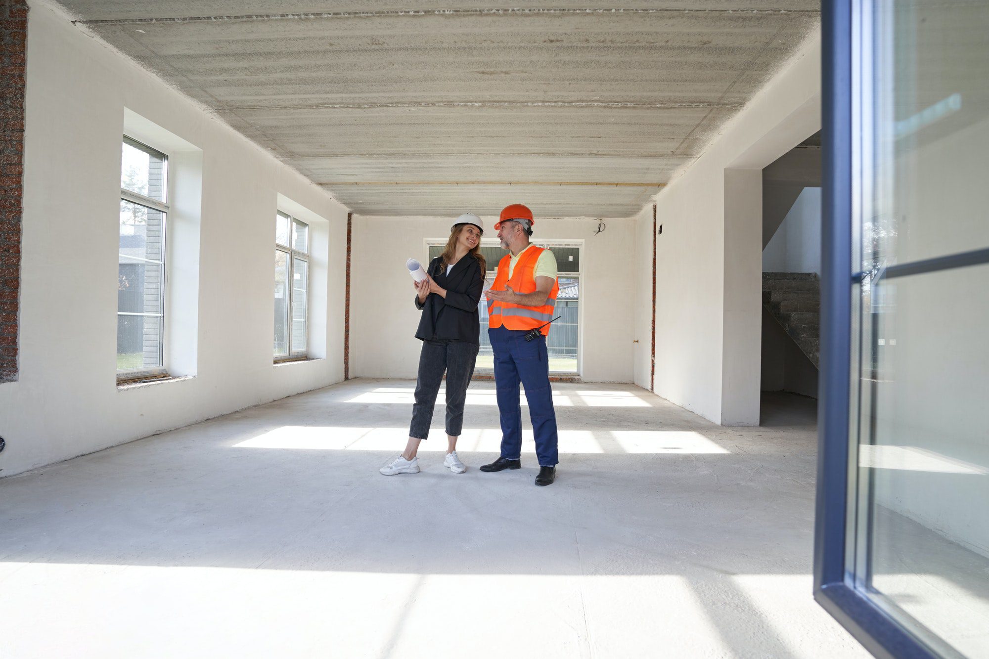 woman engineer talking with construction worker inside house